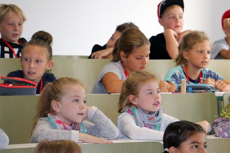 Kinder sitzen im einem Hörsaal der Hochschule Coburg.