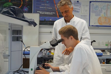 Der Koordinator des TAO-Schülerforschungszentrums, Stefan Gagel, und ein Schüler am Mikroskop