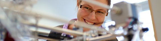 Smiling female looking at an experimental setup in the laboratory