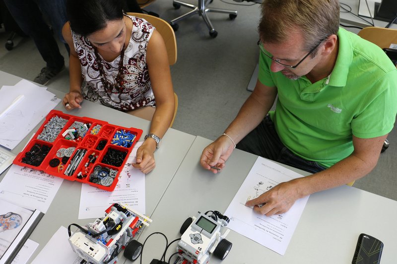 Teilnehmer eines Seminars bauen einen Lego-Fahrroboter.