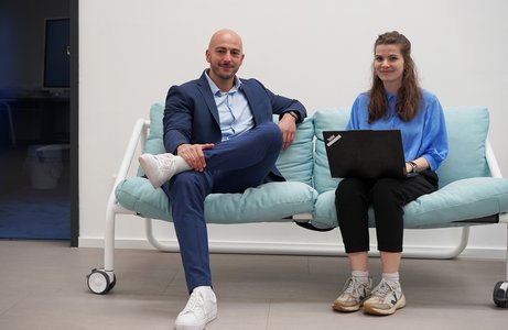 Mann und Frau sitzen auf Coauch mit Laptop.