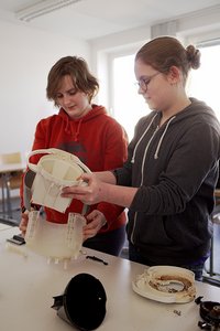 Maren Léa David und eine andere Schülerin bauen eine Kaffeemaschine auseinander