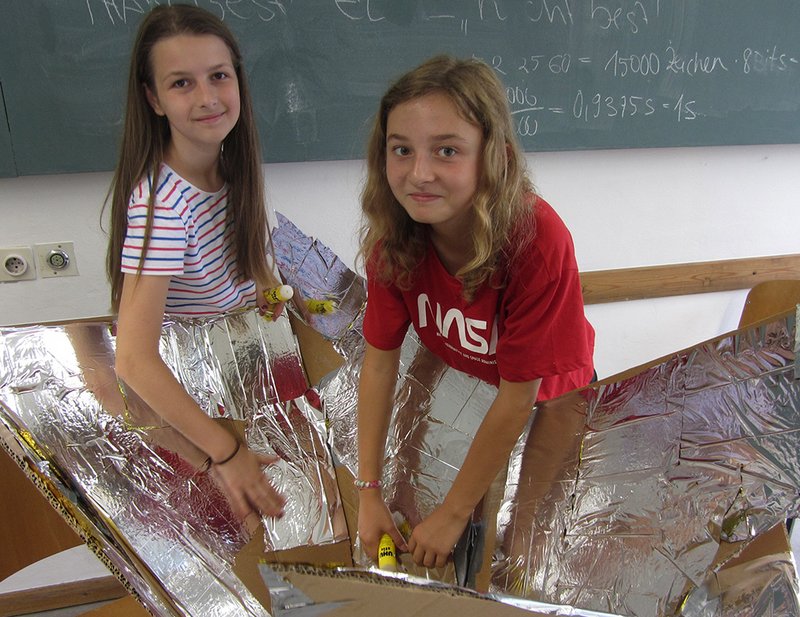 Zwei Mädchen bauen mit einem Pappkarton