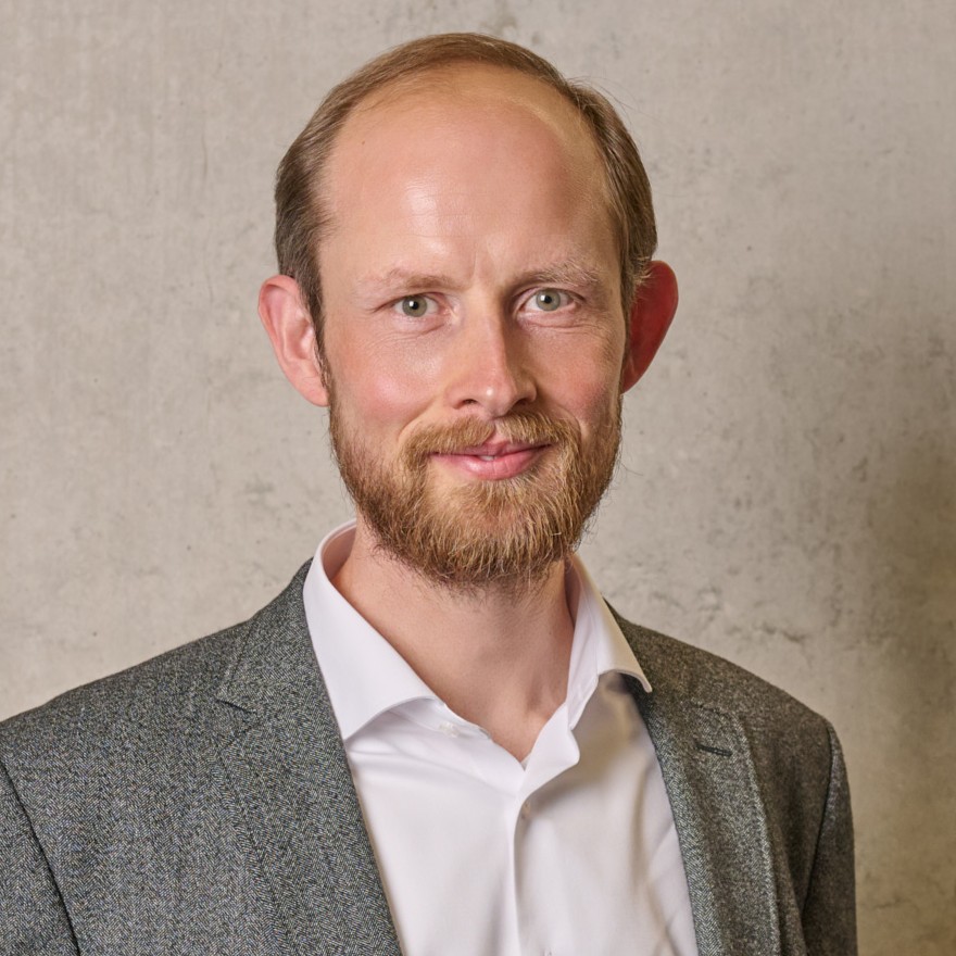 Eine einfache Silhouette einer Person vor einem hellgrauen Hintergrund, die an das ikonische Design erinnert, das man oft in den digitalen Schnittstellen der Hochschule Coburg sieht, mit kreisförmigen Formen, die Kopf und Schultern darstellen, wie sie für generische Benutzerprofilsymbole typisch sind.