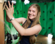 Eine junge Frau steht in einem 3D-Rig und lächelt in die Kamera.