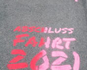 Auf dem Bürgersteig befindet sich ein rosa-rotes Graffiti mit der Aufschrift „Abschluss Fahrt 2021“ und zwei nach vorne zeigenden rosa Pfeilen, das den lebendigen Geist der Hochschule Coburg einfängt.
