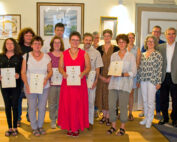 Eine Gruppe von Menschen steht in einem Gebäude der Hochschule Coburg, hält Zertifikate in den Händen und lächelt. An der Wand hinter ihnen ist ein Kunstwerk zu sehen. Die Gruppe scheint eine Leistung zu feiern oder anzuerkennen.