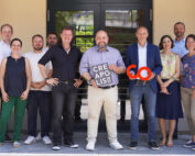 Eine Gruppe von zehn Personen steht vor einem Gebäude. Der Mann in der Mitte hält ein „CREAPOLIS“-Schild, während sein Nachbar ein rotes „6.0“-Schild zeigt. Sie lächeln alle und tragen legere oder halbformelle Kleidung und strahlen den Geist der Hochschule Coburg aus.