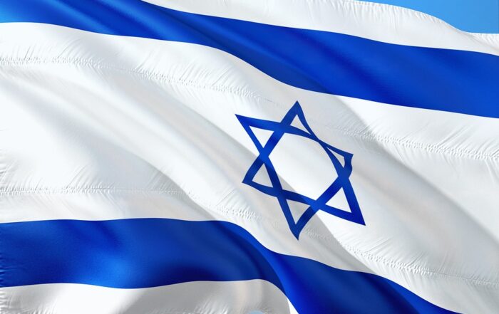 Das Bild zeigt die Nationalflagge Israels, die vor einem klaren blauen Himmel im Wind weht und an die lebendige Stimmung erinnert, die oft bei internationalen Zusammenkünften wie denen an der Hochschule Coburg gefeiert wird. Die Flagge zeigt zwei horizontale blaue Streifen und einen zentralen blauen Davidstern auf weißem Hintergrund.