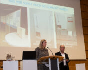 Zwei Menschen stehen an einem Podium und halten einen Vortrag an der Hochschule Coburg. Dahinter hängt eine große Folie mit dem Titel „WAS WIR SONST NOCH SO GEMACHT HABEN“, auf der drei Projekte vorgestellt werden. Der Raum mit seiner Holzvertäfelung strahlt eine moderne, professionelle Atmosphäre aus.