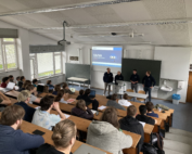 In einem Hörsaal der Hochschule Coburg herrscht reges Treiben. An Holztischen sitzen Studenten, denen vier Vortragende gegenüberstehen. Auf der Leinwand hinter ihnen wird „VAIVA“ projiziert, begleitet vom Sonnenlicht, das durch große Fenster fällt, und der klassischen Präsenz einer Tafel.