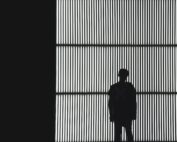 Silhouette einer Person, die vor einem großen, vertikal gestreiften Lichtpaneel in der Hochschule Coburg steht. Im dunklen Raum erzeugt das Licht einen starken Kontrast und wirft Schatten auf die Figur vor dem hellen Hintergrund.