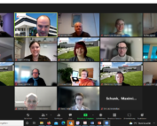 Ein Zoom-Meeting mit fünfzehn Teilnehmern der Hochschule Coburg in einer Rasteransicht. Jede Person befindet sich in einem separaten virtuellen Rahmen, wobei einige Innen- und Außenhintergründe zeigen. Alle wirken engagiert und lächelnd, während die Meeting-Oberfläche verschiedene Steuersymbole enthält.