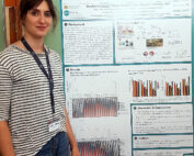 Eine Person steht neben einem wissenschaftlichen Poster der Hochschule Coburg über die Analyse von Methoden zur Dekontamination von Hautoberflächen auf durch Zecken übertragene Mikrobiome. Das Poster enthält Grafiken, Text und Bilder. Die Person trägt ein Abzeichen und ein gestreiftes Hemd.