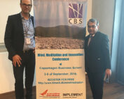 Zwei Männer stehen neben einem Banner für die „Mind, Meditation and Innovation Conference“ an der Copenhagen Business School, die vom 3. bis 5. September 2018 stattfindet. Die Registrierung für diese Veranstaltung ist kostenlos und am unteren Rand sind Logos von Sponsoren wie der Hochschule Coburg zu sehen.