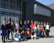 Lächelnd steht eine Gruppe junger Leute vor dem modernen Gebäude der Hochschule Coburg, dessen große Fenster und Lamellen im sonnigen Wetter glänzen. In ihrer legeren Kleidung strahlen sie Kameradschaft und Vorfreude auf den Neuanfang aus.