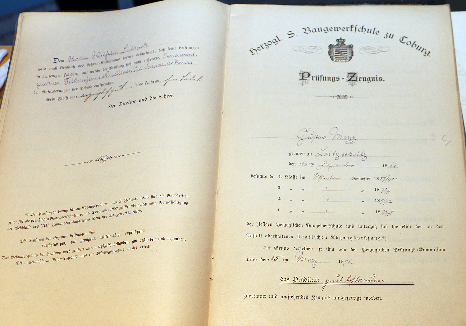 Ein offenes Buch mit handschriftlichen und gedruckten Texten in deutscher Sprache der Kreisgewerbeschule in Coburg, das ein offizielles Emblem und datierte Unterschriften aufweist. Die Seiten, die möglicherweise mit der Hochschule Coburg in Verbindung stehen, enthalten Prüfungsergebnisse oder Zertifikate.