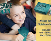 Ein lächelnder Junge hält Spielkarten in der Hand, umgeben von anderen Kindern. Eine Spielschachtel und Karten sind zu sehen. Text: „Game of Rain“, „Teste das neue Spiel!“, mit Veranstaltungsdetails: „25.06.2021, 12:00 - 15:00 Uhr, Markt Coburg.“ Präsentiert von der Hochschule Coburg.