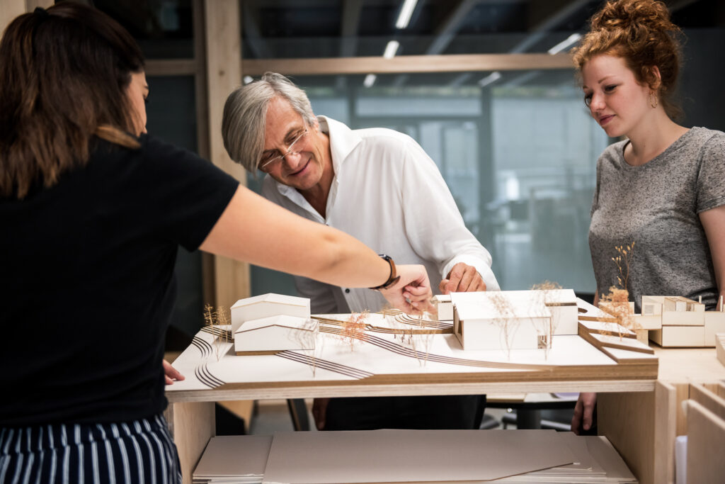 Lehrender schaut sich gemeinsam mit den Studierenden ein Architektur-Modell an