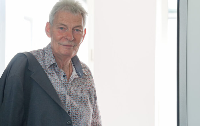Prof. Dr. Vogt, ein älterer Mann mit kurzen grauen Haaren, einem gemusterten Hemd und einer über die Schulter gehangenen Anzugsjacke, steht in einem Türrahmen, hinter dem Licht in seine Verabschiedung fällt. at Hochschule Coburg