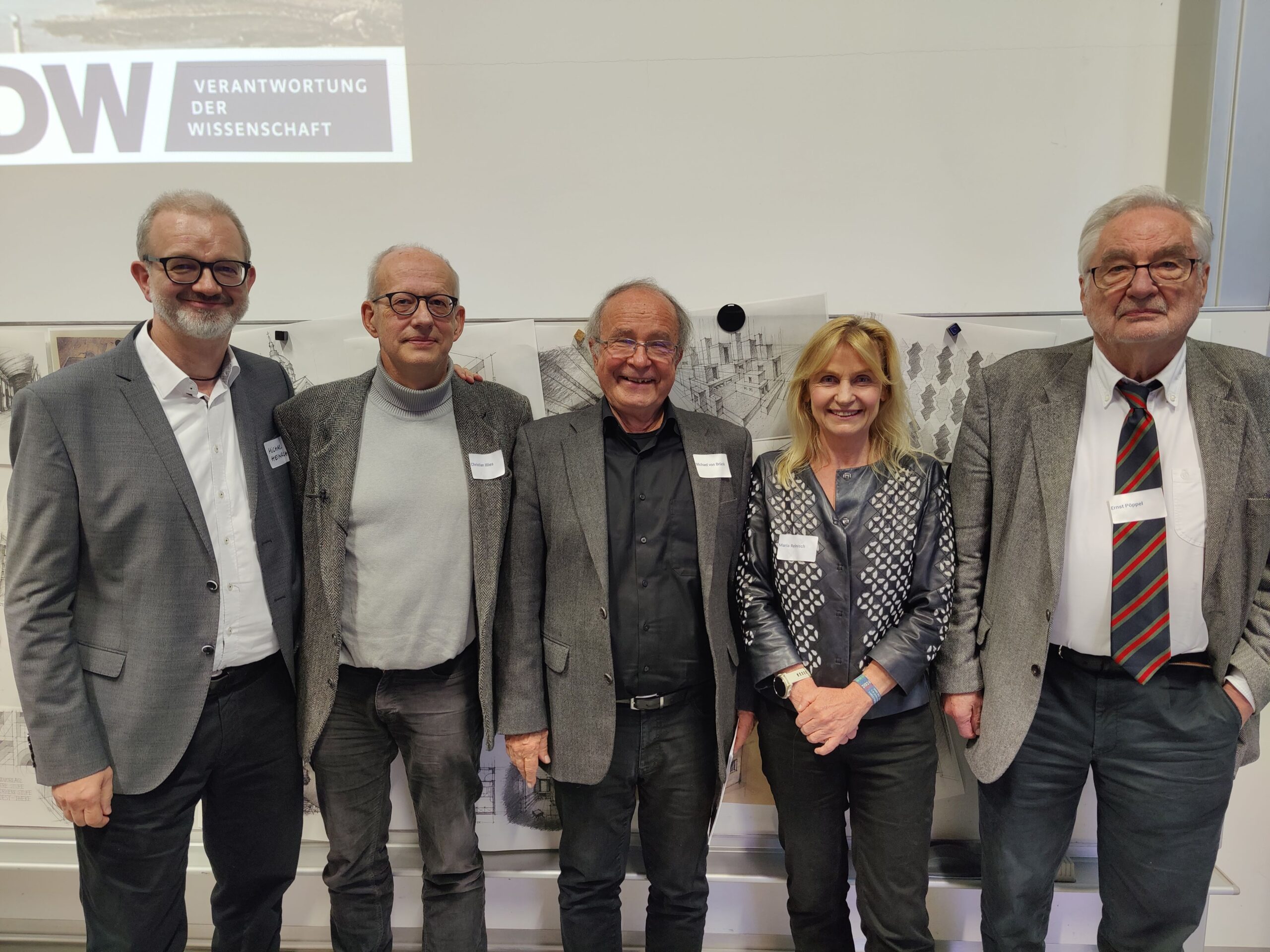 Fünf Erwachsene, drei Männer und eine Frau, lächeln beim VDW-Aktionstag in einer Hochschule vor einer weißen Wand mit dem Schild "Verantwortung der Wissenschaft" in die Kamera. Sie tragen Business-Casual-Kleidung und Namensschilder. at Hochschule Coburg