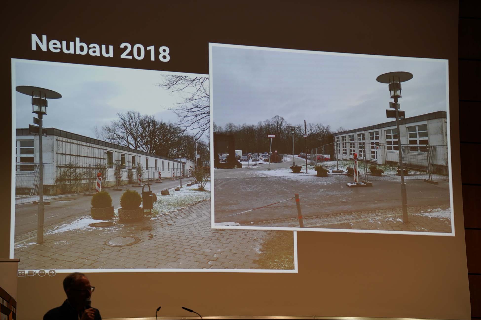 Eine Präsentationsfolie zeigt zwei Fotos eines modernen Flachbaus im Winter an der Hochschule Coburg, beschriftet mit "Neubau 2018". Im Vordergrund links unten ist die Silhouette des Vortragenden zu sehen. at Hochschule Coburg