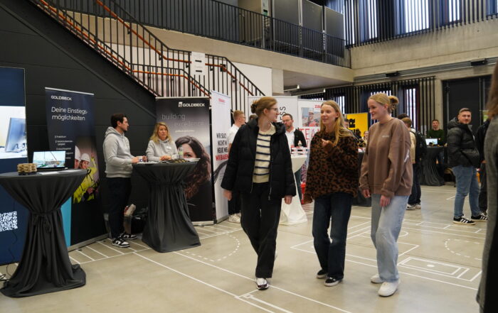 Bei einem Indoor-Karriere-Treff, bei dem sich Unternehmen an Ständen präsentieren, wird gelaufen und geredet. Die Atmosphäre ist locker, die Teilnehmer tragen Pullover und Jeans, während die Nachwuchstalente mit den sitzenden Unternehmensvertretern ins Gespräch kommen. at Hochschule Coburg