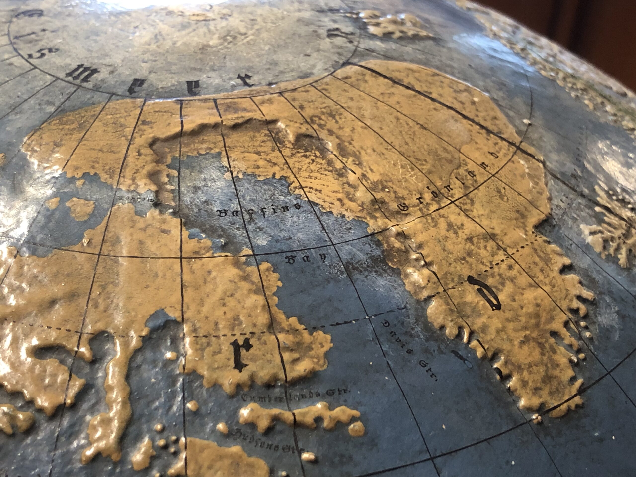 Nahaufnahme eines alten Globus, der Grönland und Teile der Arktis zeigt, mit Längengraden und verblassten, erhabenen Landmassen auf einem blauen Ozean - wie historische Karten, die Geschichten aus der Weltgeschichte erzählen. at Hochschule Coburg