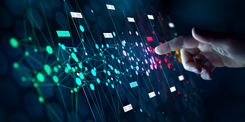 A hand pointing at a colorful digital interface displaying interconnected data nodes and lines, representing complex computer science technology or data analysis on a dark background. at Hochschule Coburg
