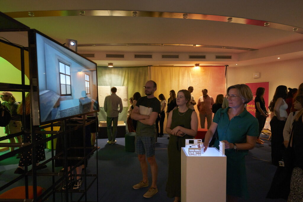 Coburger Studierende in einer Galerie, die sich ein digitales Display und ein Architekturmodell von Goethes Arbeitszimmer auf einem Sockel ansehen. at Hochschule Coburg