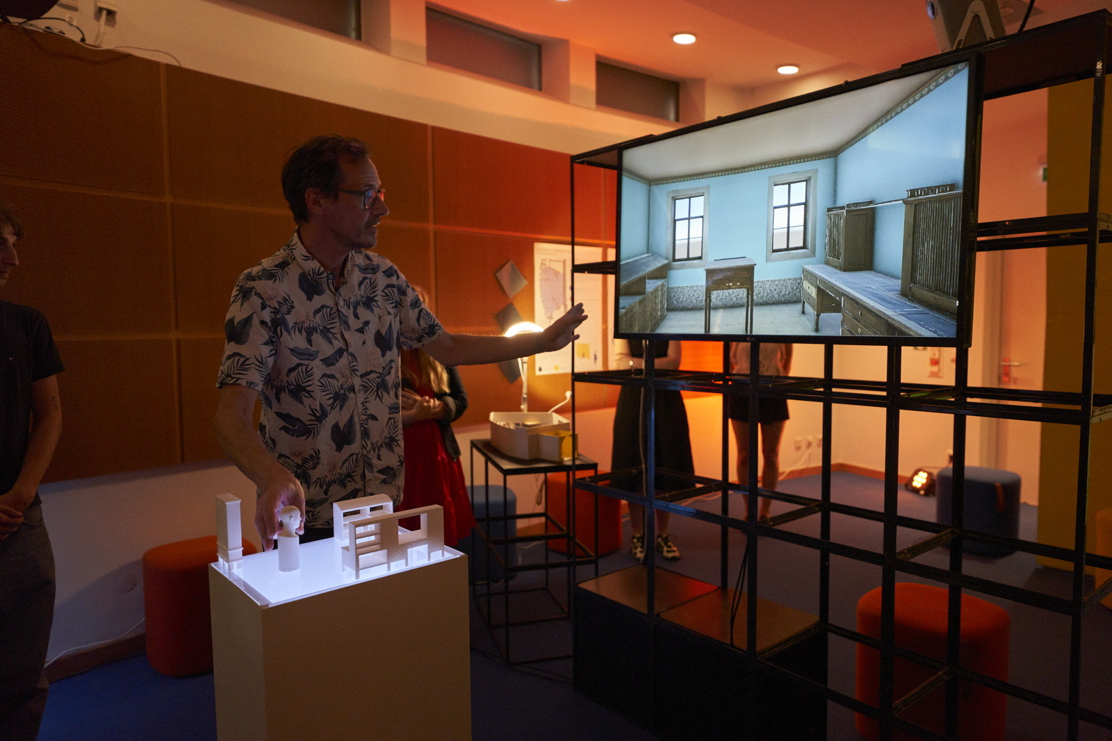 Ein Student aus Coburg interagiert mit einem physischen Architekturmodell, das eine digitale Simulation von Goethes Arbeitszimmer steuert, die auf einem Bildschirm angezeigt wird. at Hochschule Coburg