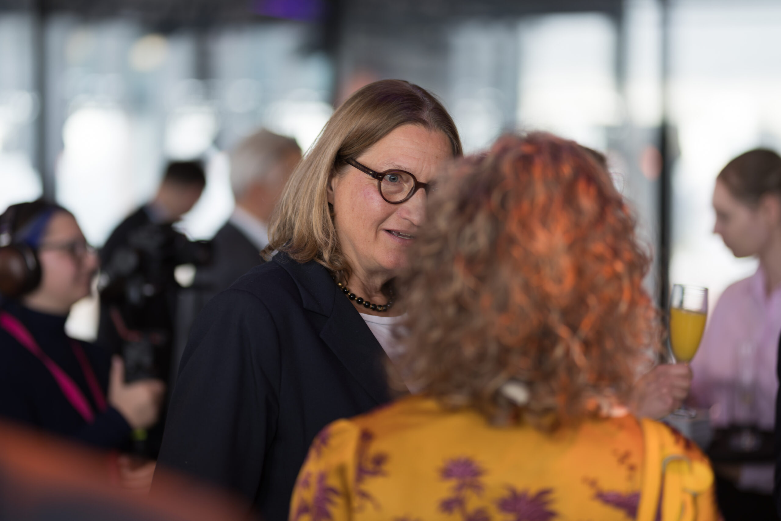 Eine Frau in einem dunklen Blazer und mit Brille unterhält sich beim Jubiläum der Hochschule Bayern in Coburg mit einer anderen Frau. at Hochschule Coburg