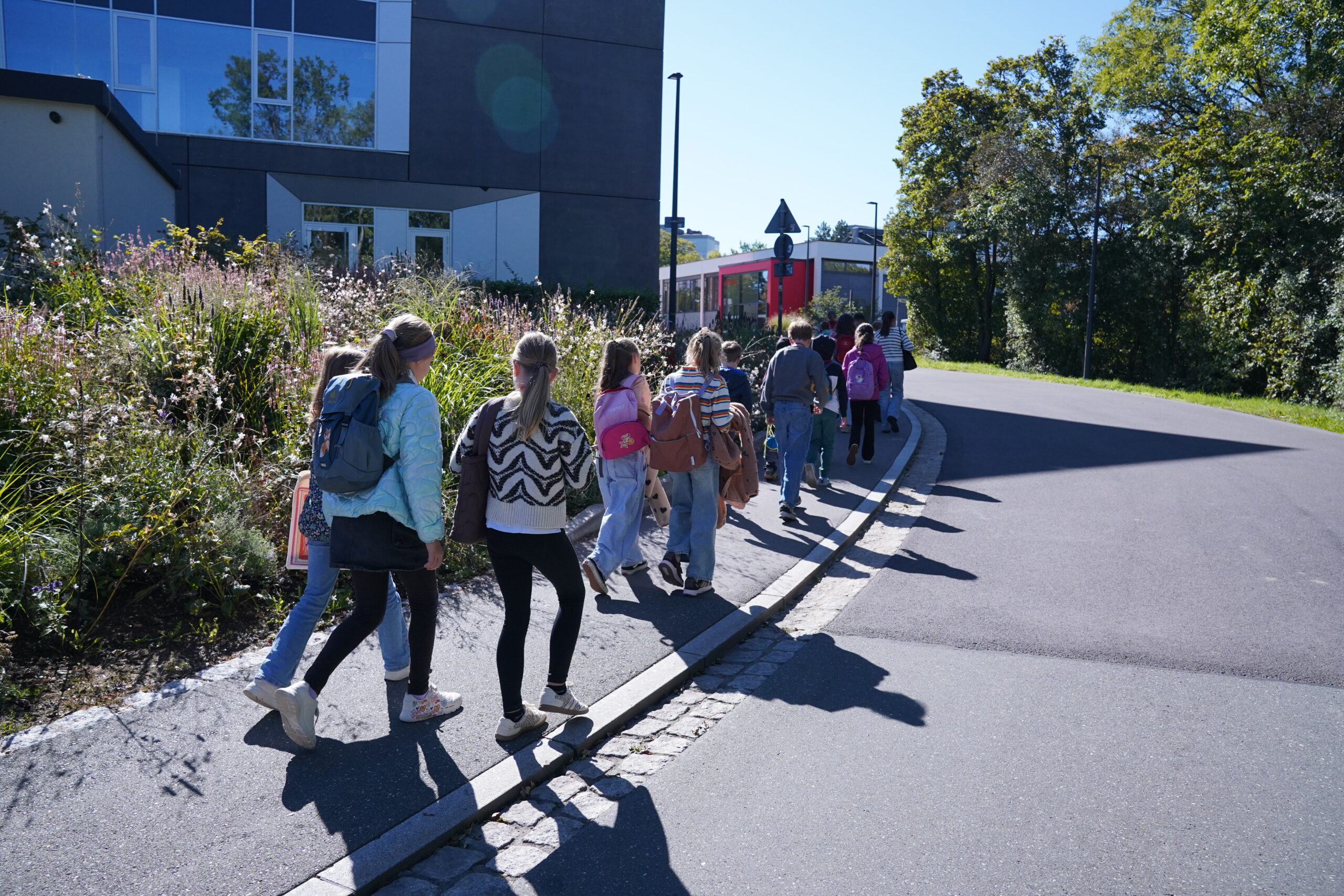 Eine Gruppe von Kindern der KinderUni läuft an einem sonnigen Tag in einer Reihe auf einem Bürgersteig entlang. at Hochschule Coburg