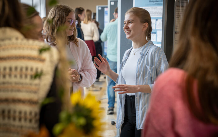 Zwei Studierende diskutieren bei einer wissenschaftlichen Veranstaltung über Forschungsplakate zum Thema automatisiertes Design. at Hochschule Coburg