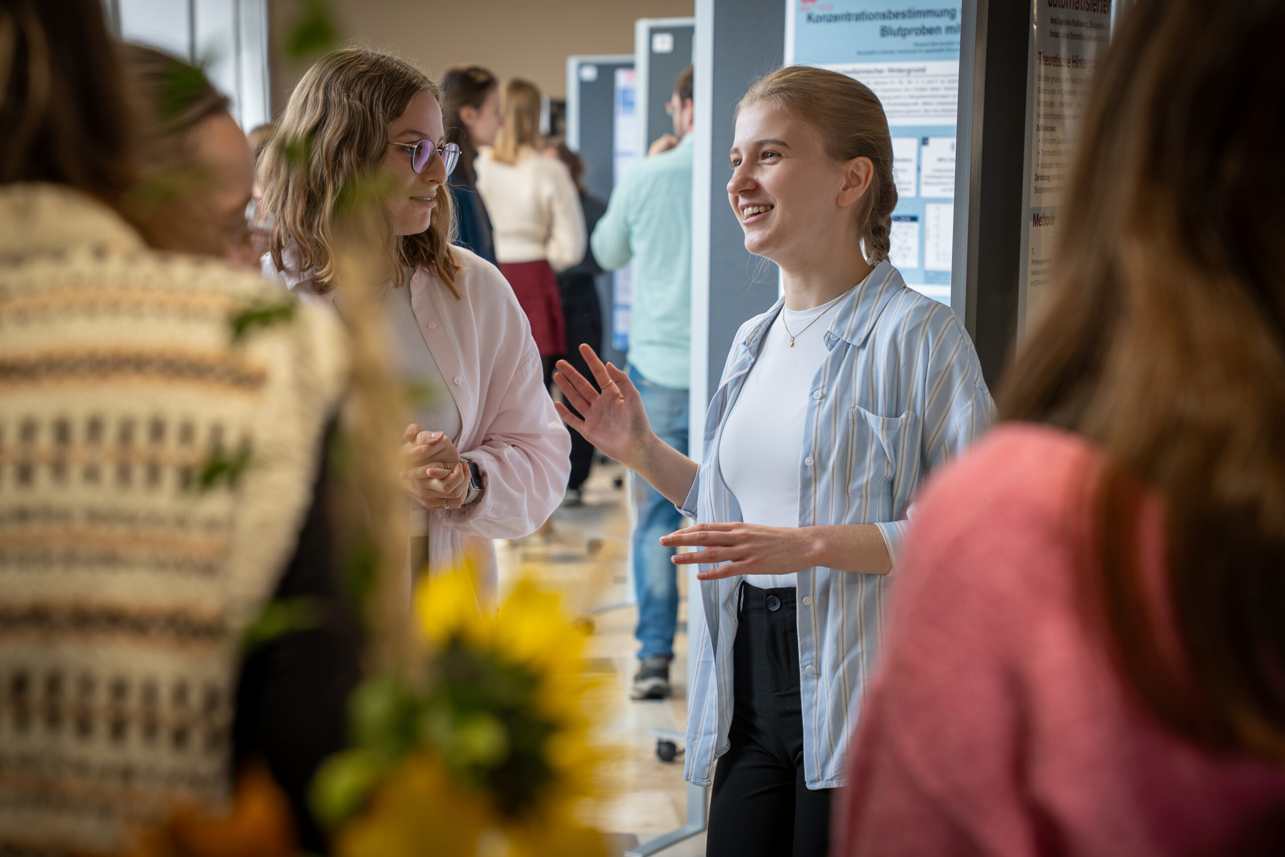 Zwei Studierende diskutieren bei einer wissenschaftlichen Veranstaltung über Forschungsplakate zum Thema automatisiertes Design. at Hochschule Coburg