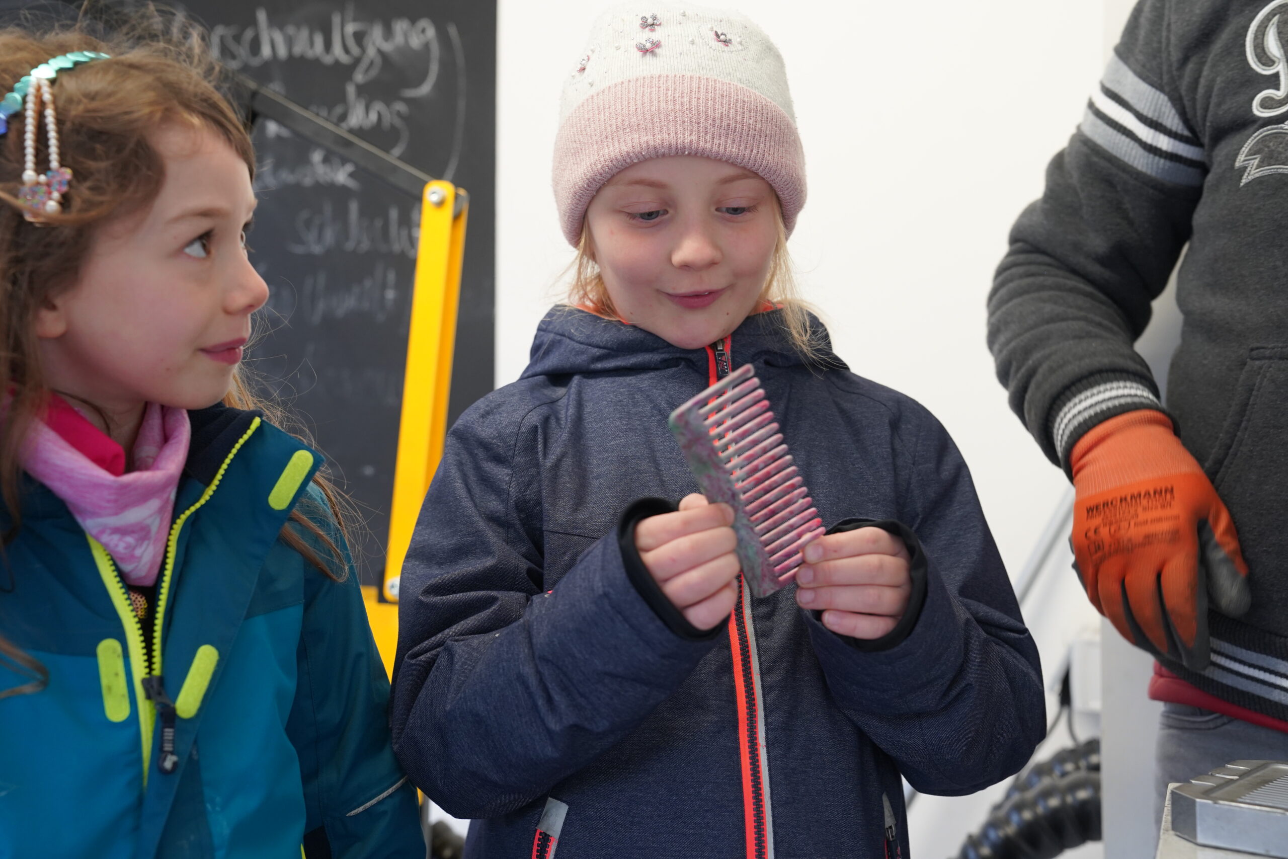 Ein junges Mädchen mit Wintermütze und Jacke betrachtet einen kleinen, bunten Plastikkamm mit der Konzentration eines automatisierten Entwurfs. at Hochschule Coburg