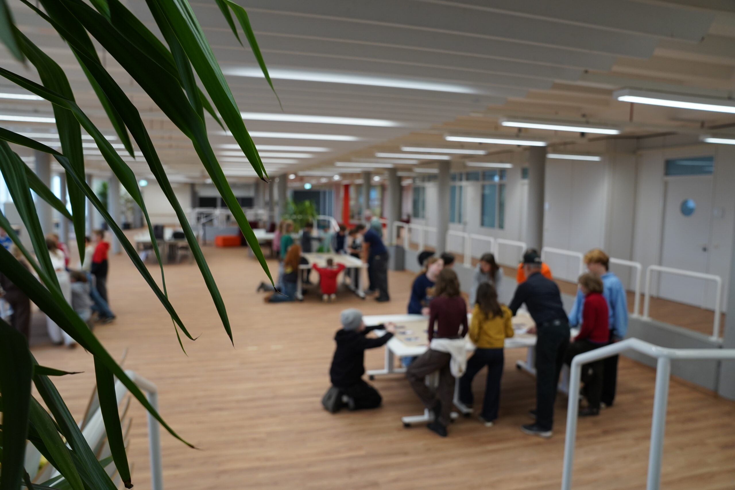 Eine Gruppe von Menschen, die in einem großen, offenen Büroraum gemeinsam an einem Designprojekt arbeiten. at Hochschule Coburg