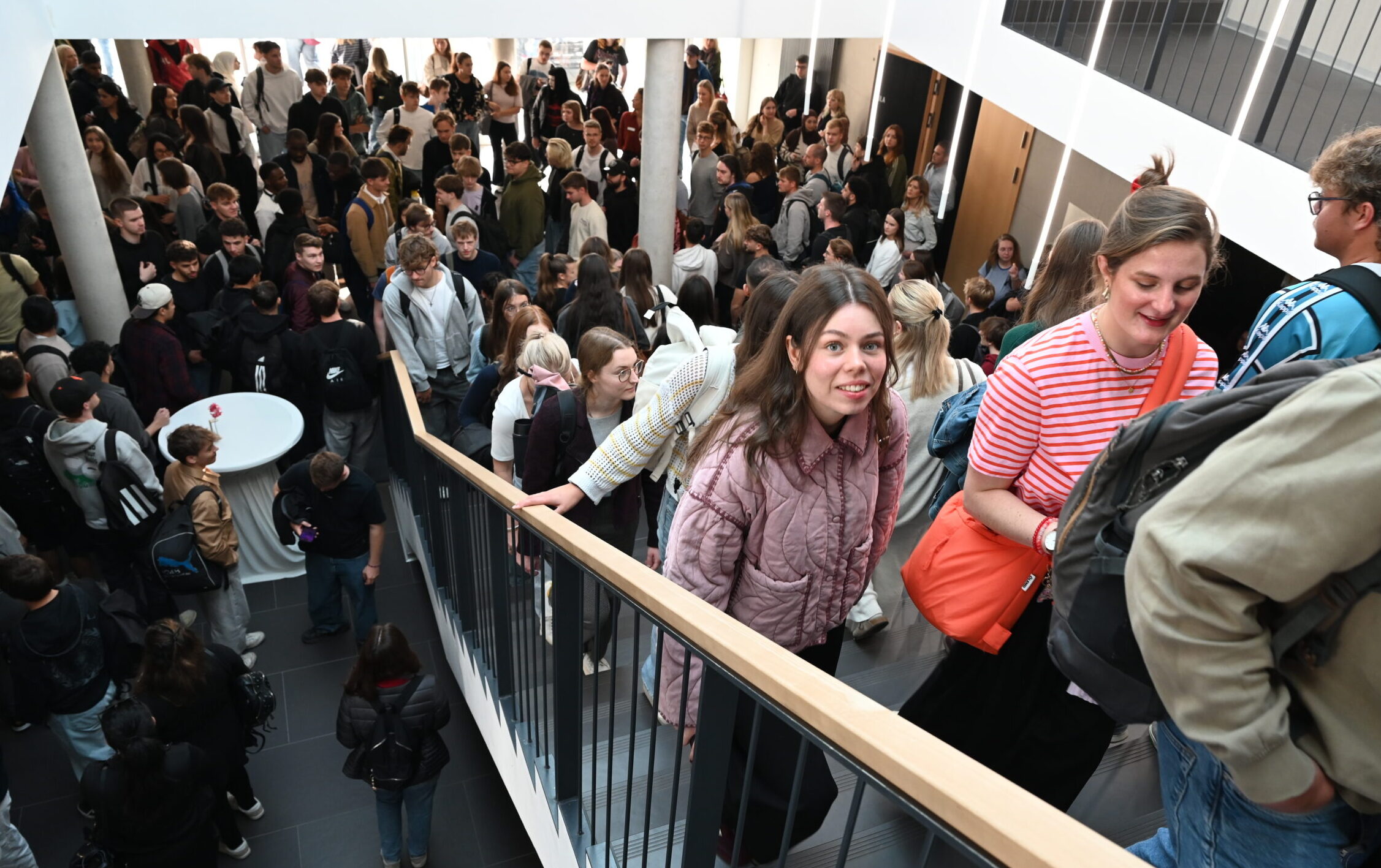 Eine große Gruppe von Studierenden der Hochschule Coburg, die in einem mehrstöckigen Gebäude eine Treppe hinauf- und hinuntergehen. at Hochschule Coburg