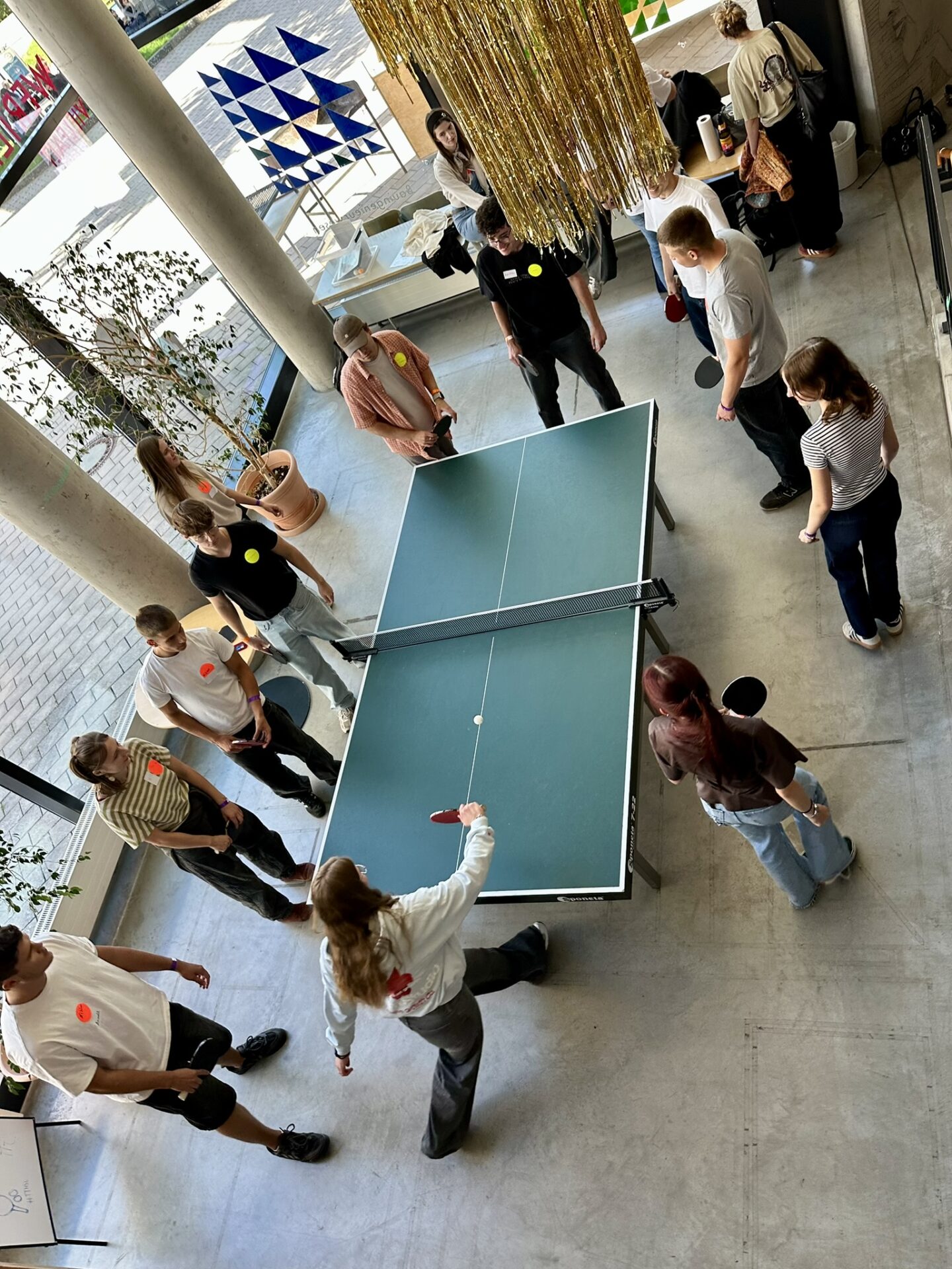 Eine Gruppe von Menschen steht während eines Spiels an der Hochschule Coburg um einen Tischtennistisch herum. at Hochschule Coburg