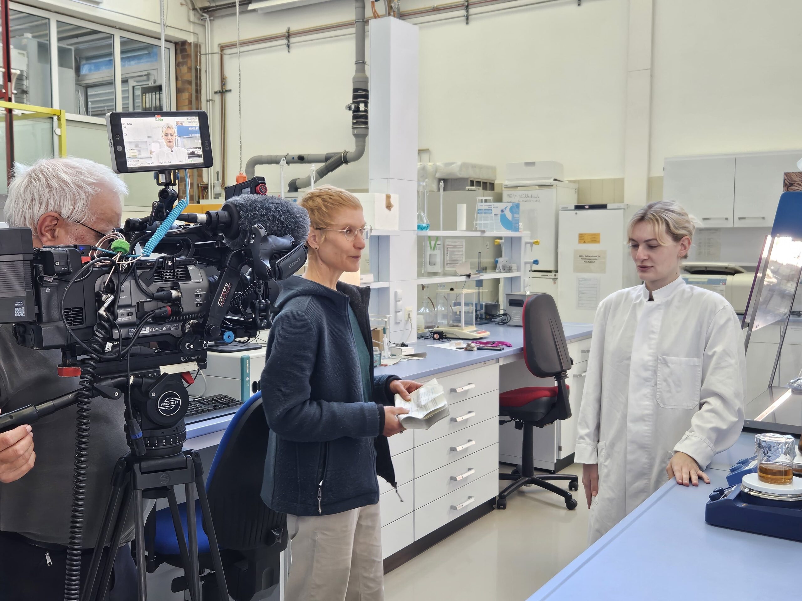 Ein Kameramann filmt eine Frau, die in einem Labor einen Wissenschaftler zum Thema automatisiertes Design interviewt. at Hochschule Coburg