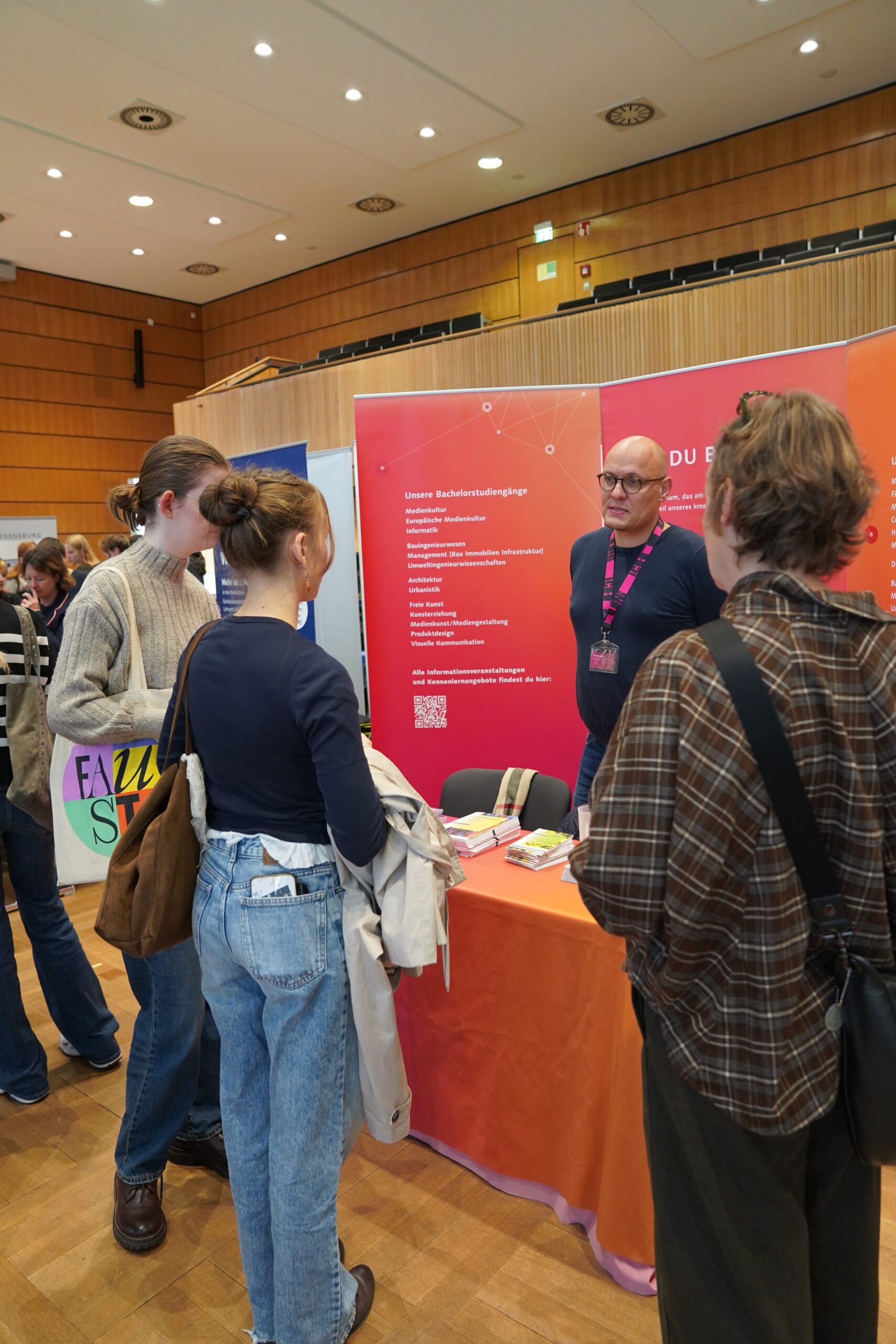 Drei Studierende lassen sich an einem Informationsstand der Coburger Studienmesse von einem Vertreter akademisch beraten. at Hochschule Coburg