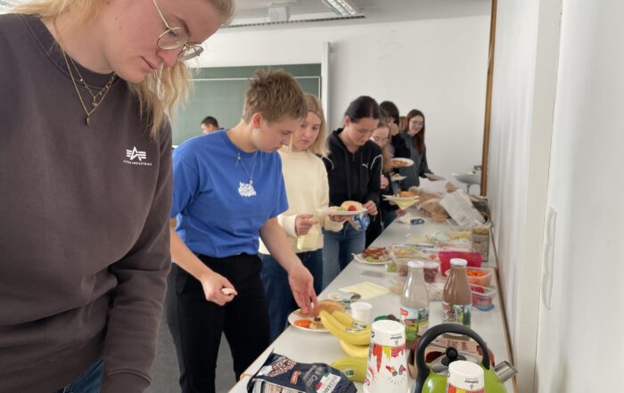Eine Reihe von MINT-Studierenden, die sich an einem Buffettisch, der in einem Raum für ihren Studienanfang aufgestellt wurde, Essen nehmen. at Hochschule Coburg
